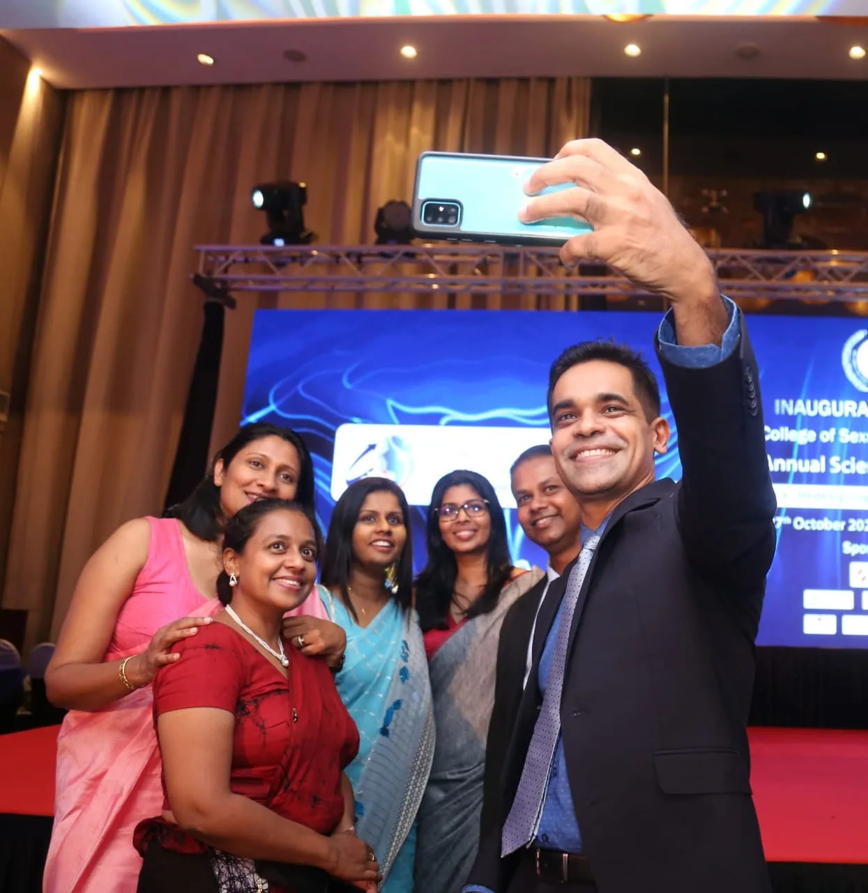 Dr. Prageeth taking a selfie with colleagues at an event.